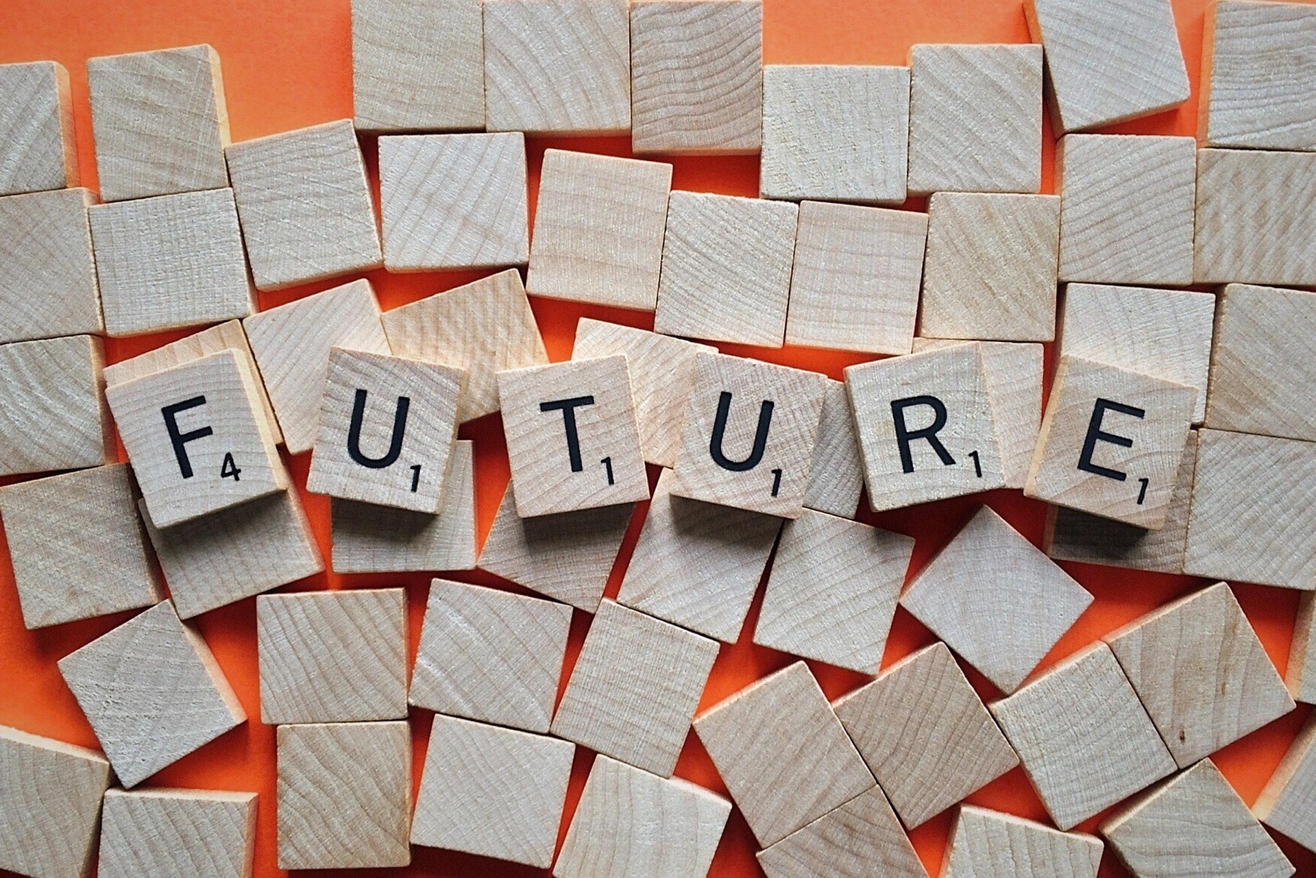 Holzbuchstaben-Fliesen bilden das Wort „Future" auf orangem Untergrund – Sinnbild für Future Skills